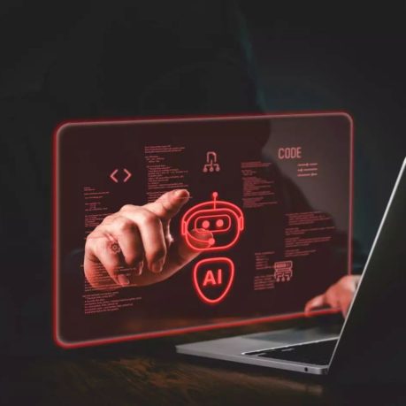 En person pekar på en digital röd hologramdisplay med AI-symboler och kod framför en laptop.